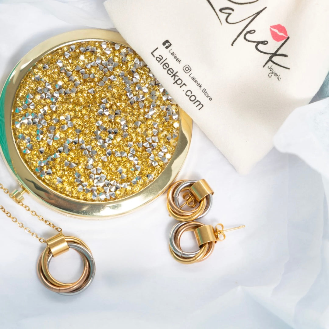 Gold jewelry set including necklace, earrings, and round gold compact mirror on a white background with 'Laleek' branding.