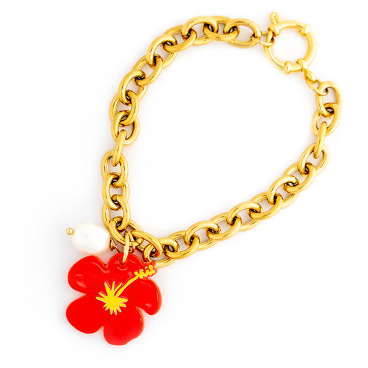 Gold chain bracelet with a red flower charm on a white background