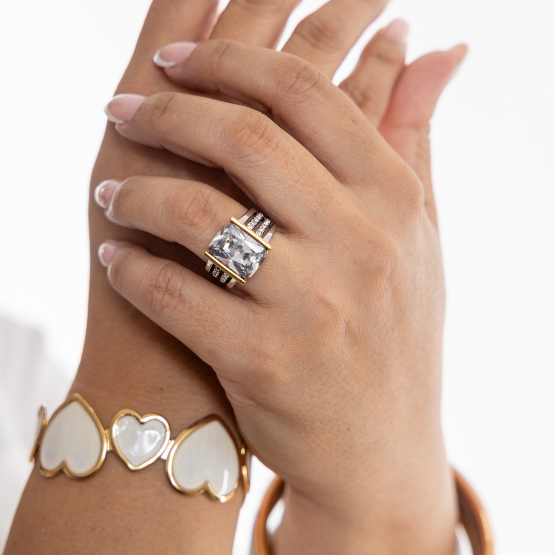 Hand wearing a gold ring with a diamond on a white background
