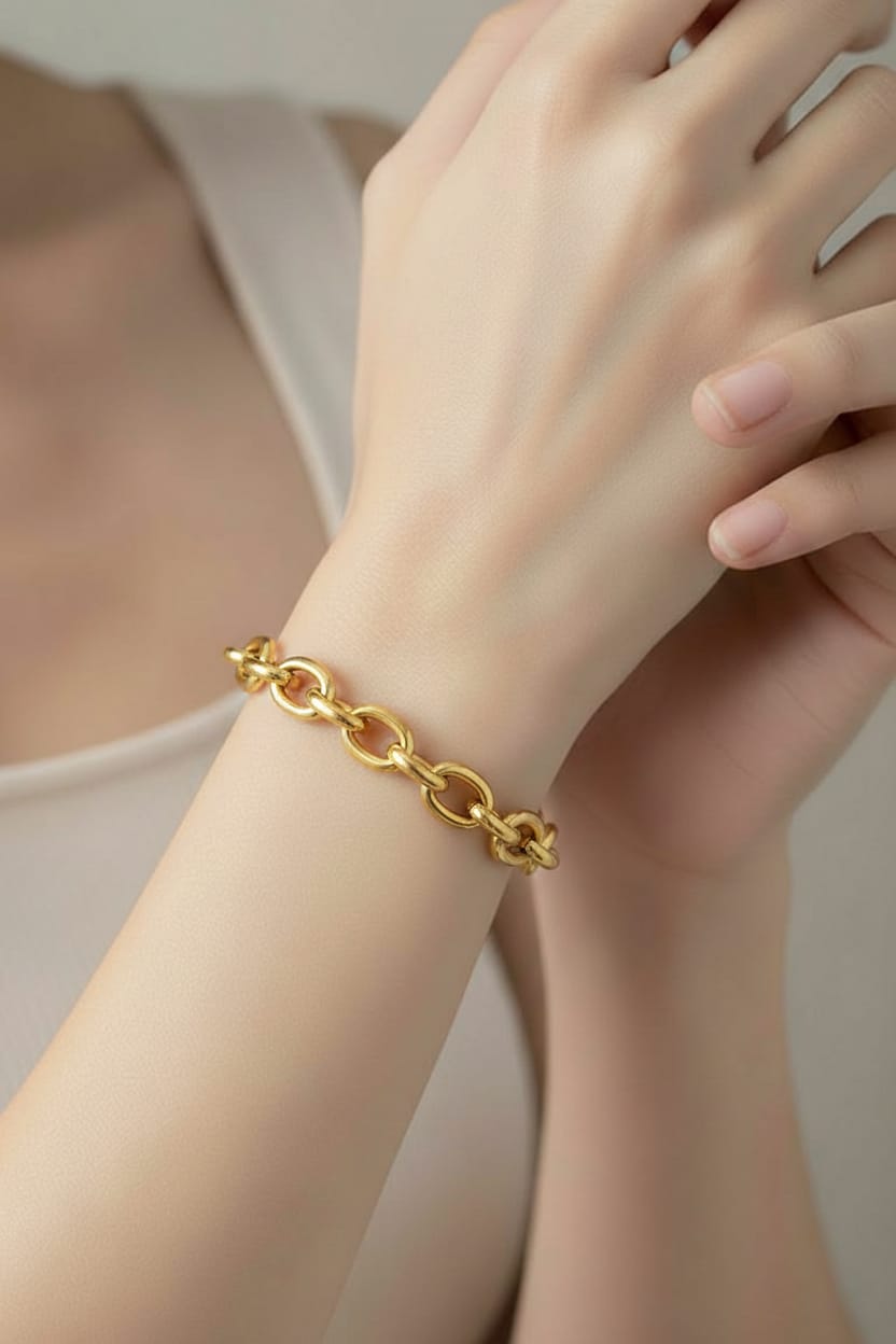 Gold chain bracelet on a wrist with a neutral background