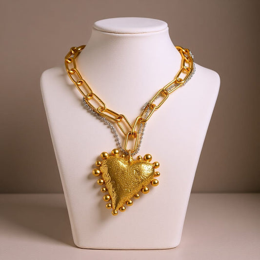Gold necklace with a heart pendant on a mannequin bust against a neutral background