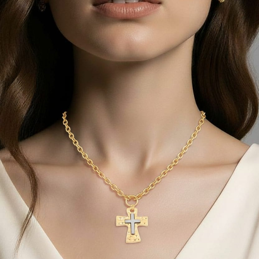 Gold necklace with a cross pendant worn by a model against a neutral background
